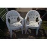 Four white plastic stacking patio chairs.