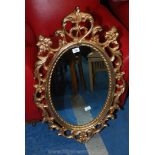 A gilt finish oval wall mirror.