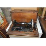 A hand sewing machine in wooden case.