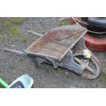 A small wooden framed child's wheelbarrow with four spoke metal rimmed wheel.