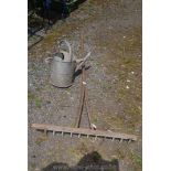 A wooden hay rake and a galvanised watering can.