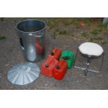 A galvanised dustbin, fuel cans and stool.