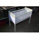 A white cot with mattress.