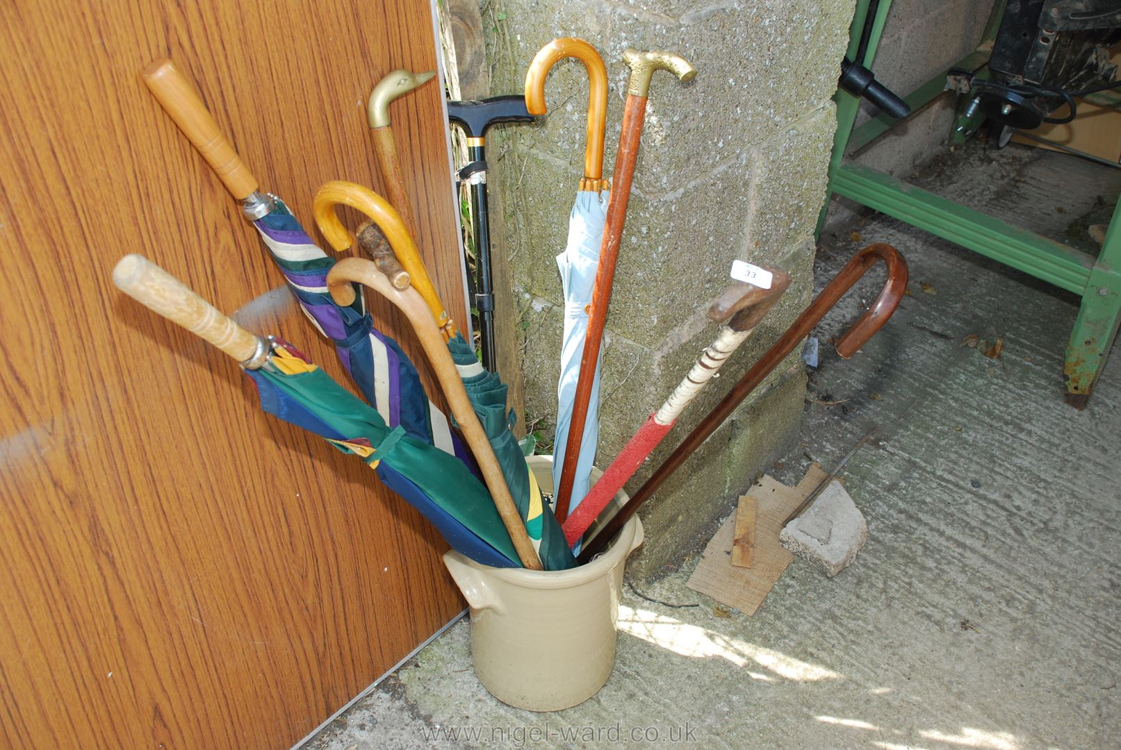 A bread crock and a quantity of umbrellas and walking sticks.