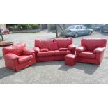 A red hide upholstered lounge suite comprising a three-seater settee and a pair of chairs.