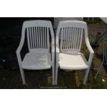 Two white plastic stacking patio chairs.