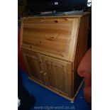 A pine writing bureau with two door cupboard.