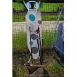 An ironing board, garden plant stand, walking stick, bird feeders and rounders bat.