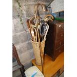 A large quantity of various walking sticks and shooting stick in a seagrass basket.