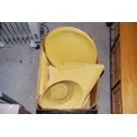 A box of large round and triangular platters and plates, yellow in colour.