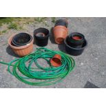 A quantity of plastic flower pots and garden hoses.