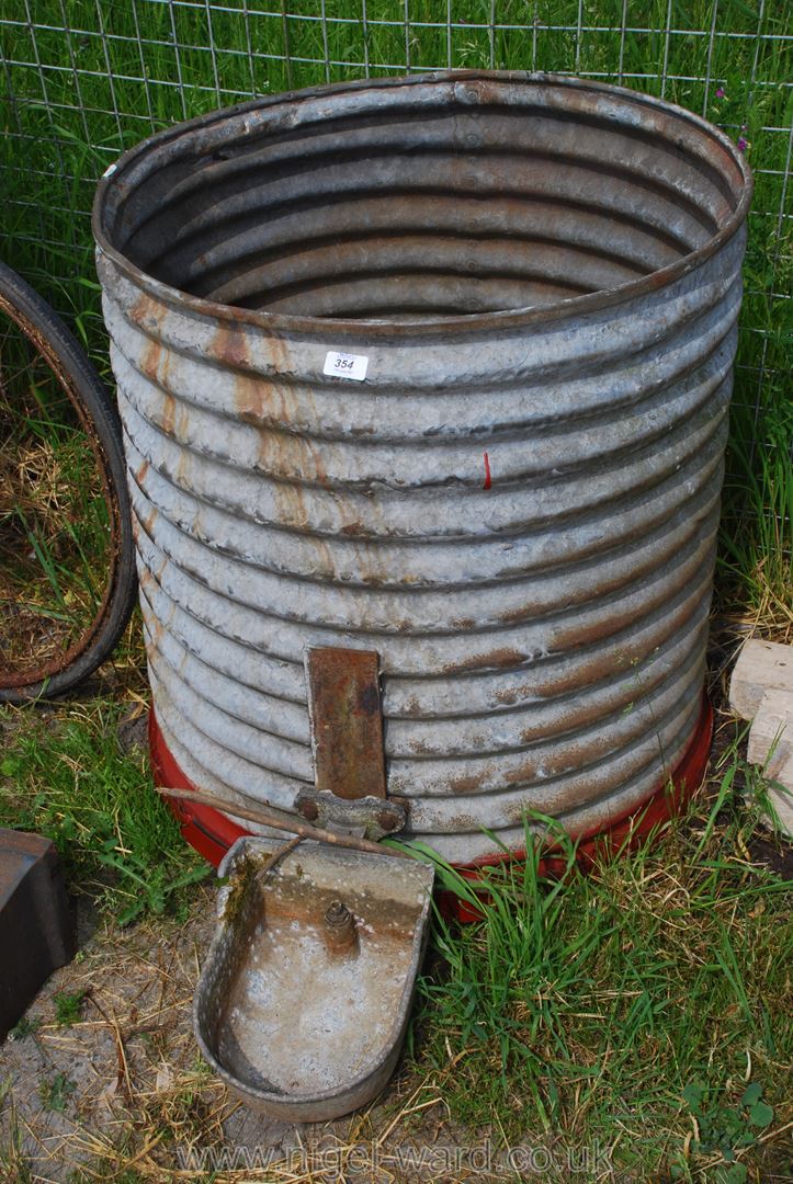 A circular galvanised water butt with drinker.