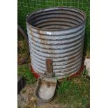 A circular galvanised water butt with drinker.