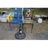 Two painted metal patio chairs and a parasol base.