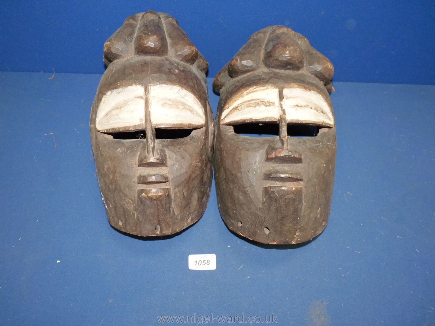 Two hand carved African face masks with white painted eyes, lightweight, possibly cork, 12" tall.