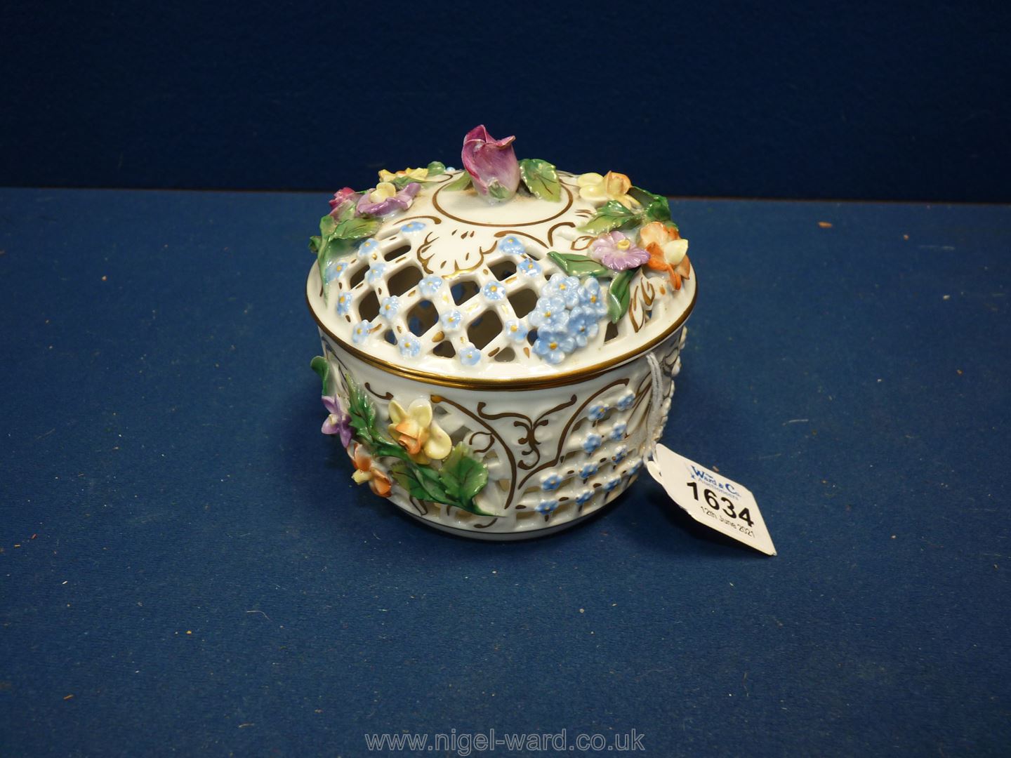 An exquisite Dresden lidded pot with pastel coloured encrusted flowers and lattice work panels