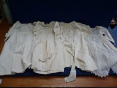 Four ivory christening/infant gowns, one tagged 'Celia Jones, 150 years old'.
