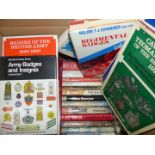 A box of books including military badges and war books.