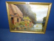 A framed Oil on board depicting a riverside thatched cottage and garden, signed lower right J.