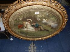 A highly ornate oval framed coloured lithograph depicting a couple sat by the side of a river with