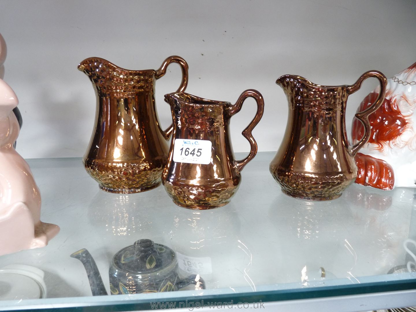 A set of three graduated copper Lustre ware jugs.