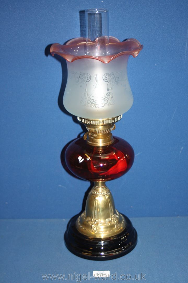 A Nouveau style brass Oil lamp with cranberry glass reservoir and fluted etched shade,