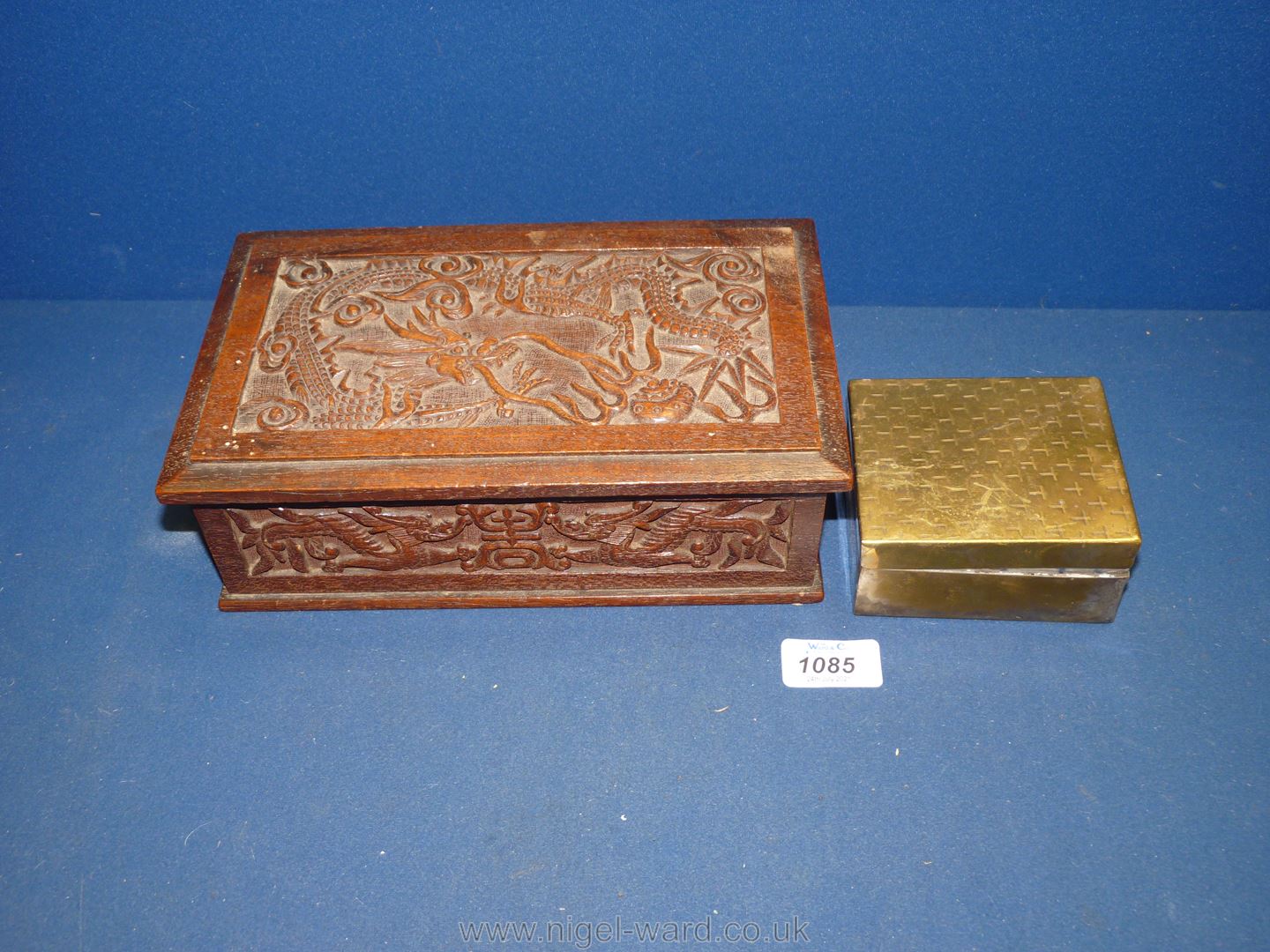 A hand carved box with oriental scenes and a brass cigarette box.