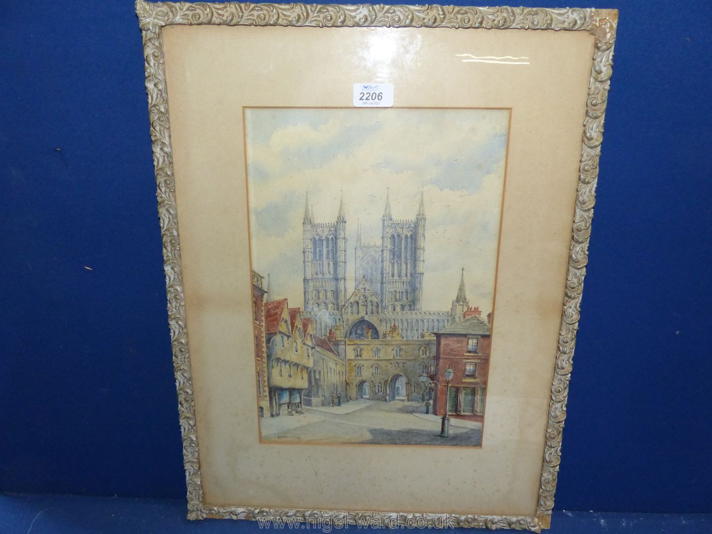 A framed and mounted watercolour depicting a street and a Cathedral, signed lower left 'L.M.