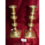 A pair of brass candlesticks with pushers.