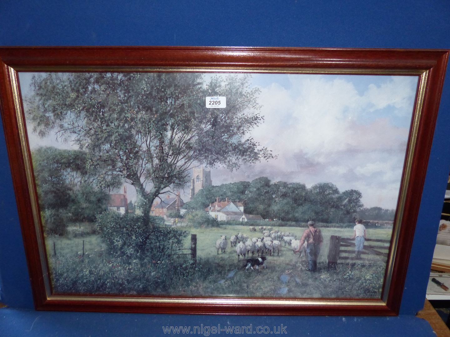 A large print depicting a village scene with farmer driving sheep through to the next field with a