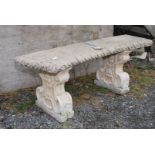 Curved concrete garden bench standing on two pedestal legs
