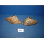 Two carved small clogs formed out of both sides of a cow hoof.