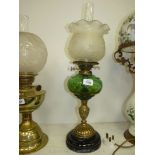 An oil lamp with brass stand, dark green reservoir, frosted fluted shade with relief decoration,