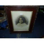 A large wooden framed picture taken from a photograph of a young girl in antique frame.