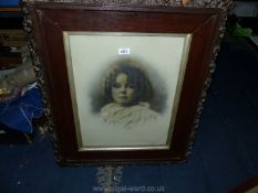 A large wooden framed picture taken from a photograph of a young girl in antique frame.