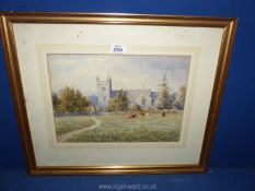 A framed and mounted watercolour of cattle grazing the pasture by a village church,