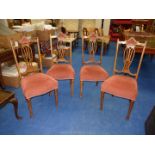 Four dining chairs with salmon coloured seats and backs.