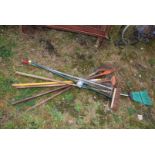 A quantity of garden rakes and brooms.