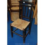 A seagrass seated stick back style chair having finely carved detail hardly visible on camera.