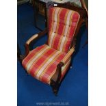 An Edwardian mahogany/walnut framed open armed fireside chair standing on turned front legs and