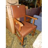 An Oak framed open-armed Elbow Chair on turned front legs and with an 'H' stretcher and brass