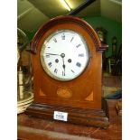 A Mantle clock with Roman numerals, marquetry detailing to the front.