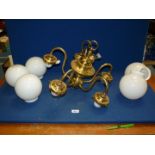 A five branch brass ceiling light with white globe shades.