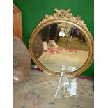 A gilt coloured circular mirror with crossed torches to top, some damage to base of mirror,