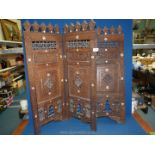 A Moroccan style three panel screen; panels highly carved with Mother of Pearl inlay.