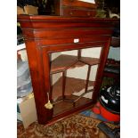 A circa 1900 Mahogany wall-hanging corner cabinet having geometrically glazed seven pane door,