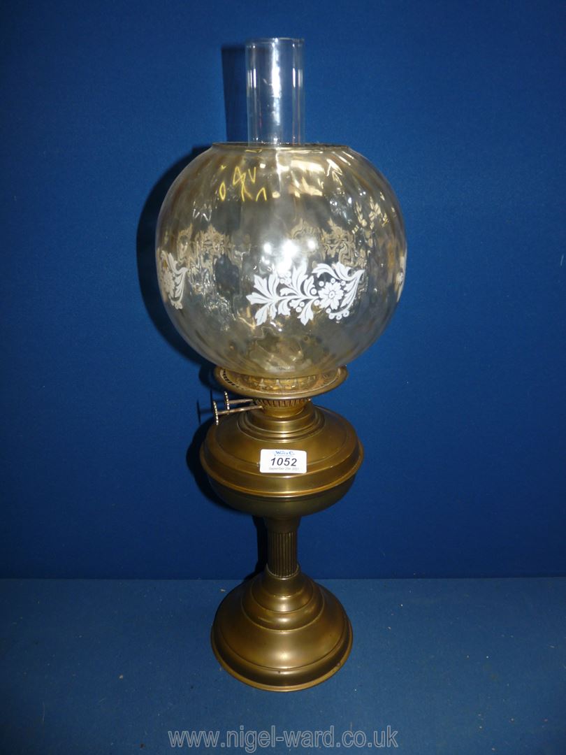 A Victorian oil lamp with clear globe, white with flowers, on brass base with chimney, 23" tall.