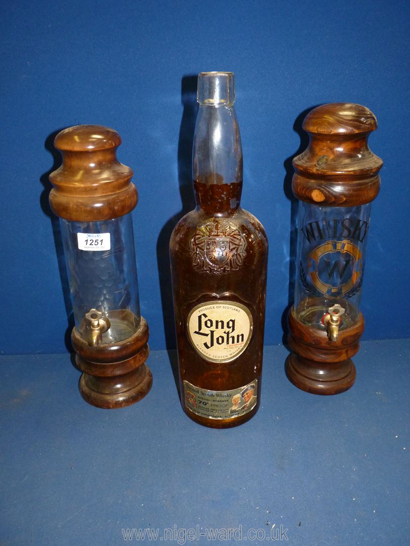 Two unusual decanters on wooden plinths with brass taps and wooden lids;