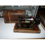 A Singer sewing machine in black and gold in wooden case.