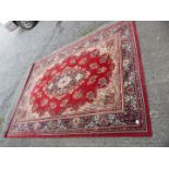 A border patterned Kashmir wool rug with blue and yellow central motif on red ground,